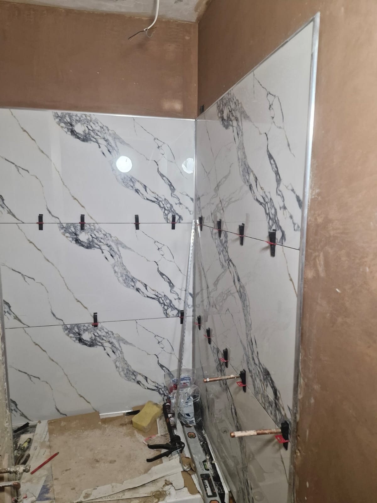Marble-effect wall tiles being fitted in a bathroom