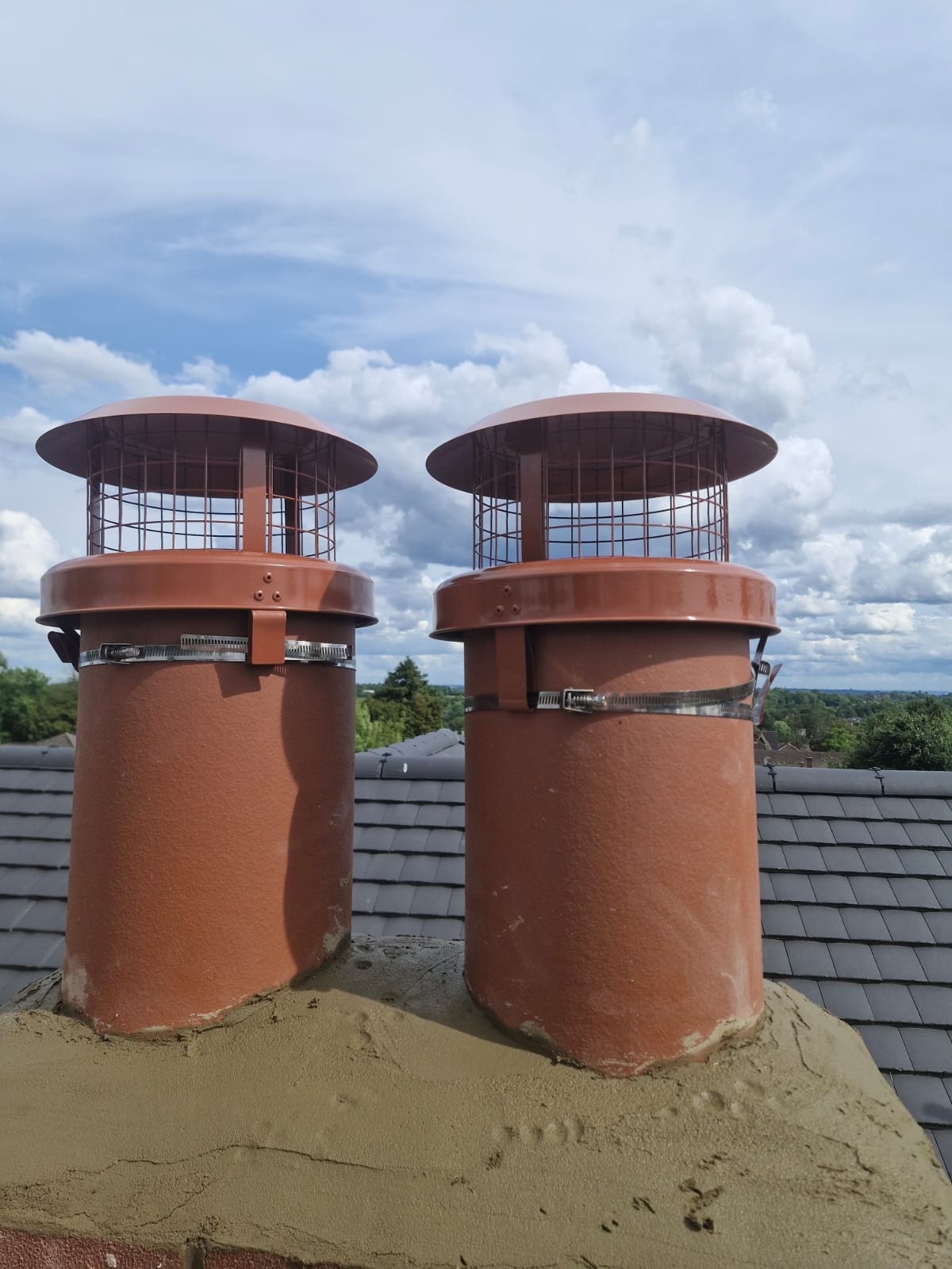 Chimney cowls installed on two chimney pots