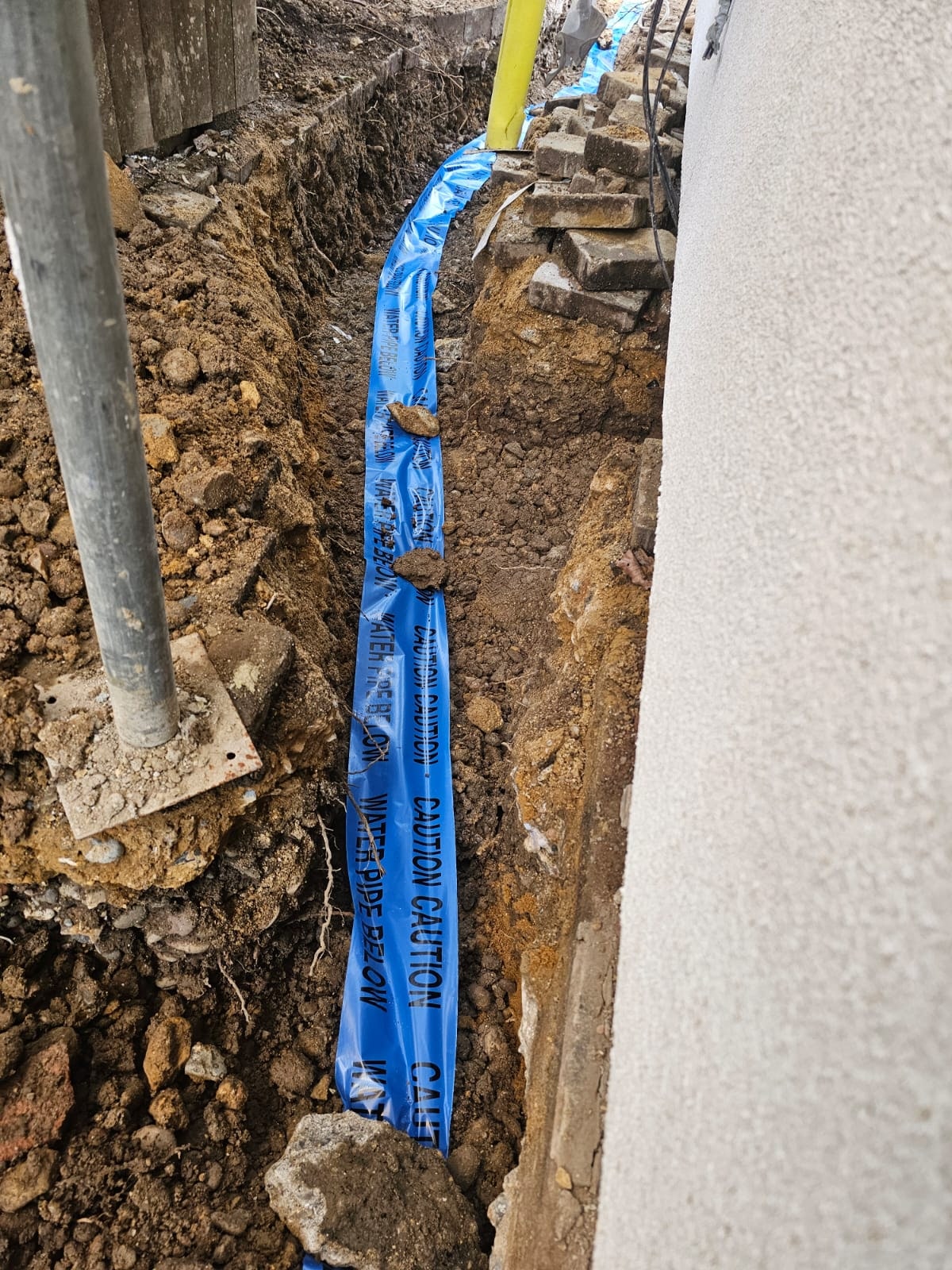 Blue drainage pipe installed in a narrow trench