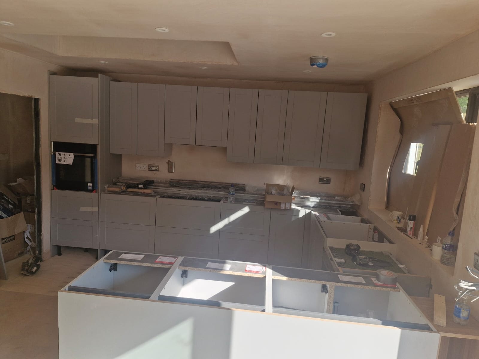 Kitchen units and worktops being fitted in a bright room